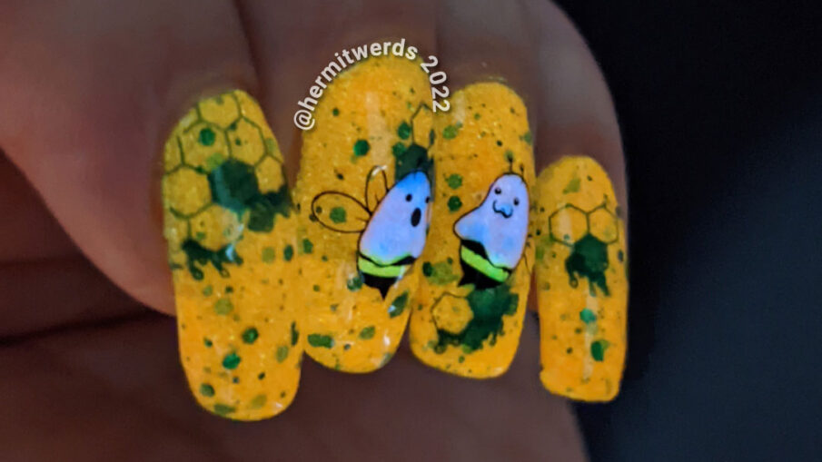 A punany bee nail art with stamping decals of ghost bees (boo bees) on a bright orange crelly with green glitter that glows orange in the dark.