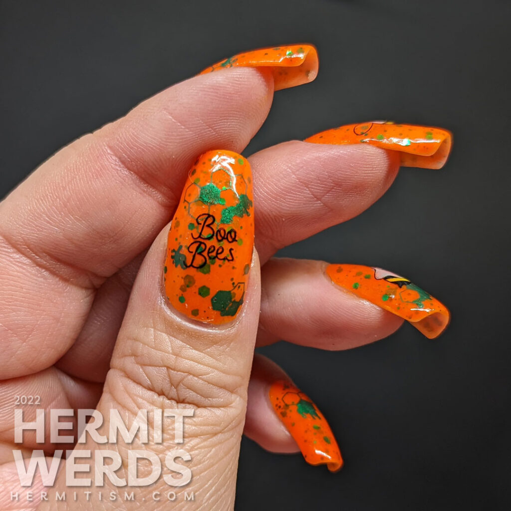 A punny bee nail art with stamping decals of ghost bees (boo bees) on a bright orange crelly with green glitter that glows orange in the dark.