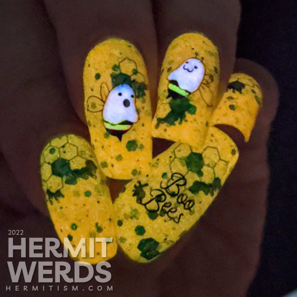A punny bee nail art with stamping decals of ghost bees (boo bees) on a bright orange crelly with green glitter that glows orange in the dark.