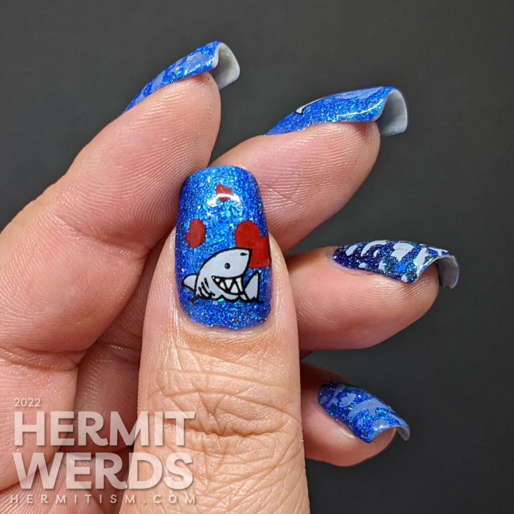 Shark nail art with cute sharks who have taken bites out of hearts as stamping decals on a glitzy blue base polish.