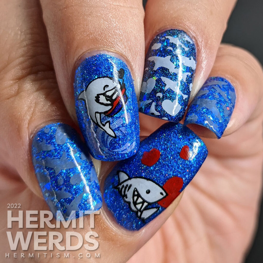 Shark nail art with cute sharks who have taken bites out of hearts as stamping decals on a glitzy blue base polish.Shark nail art with cute sharks who have taken bites out of hearts as stamping decals on a glitzy blue base polish.