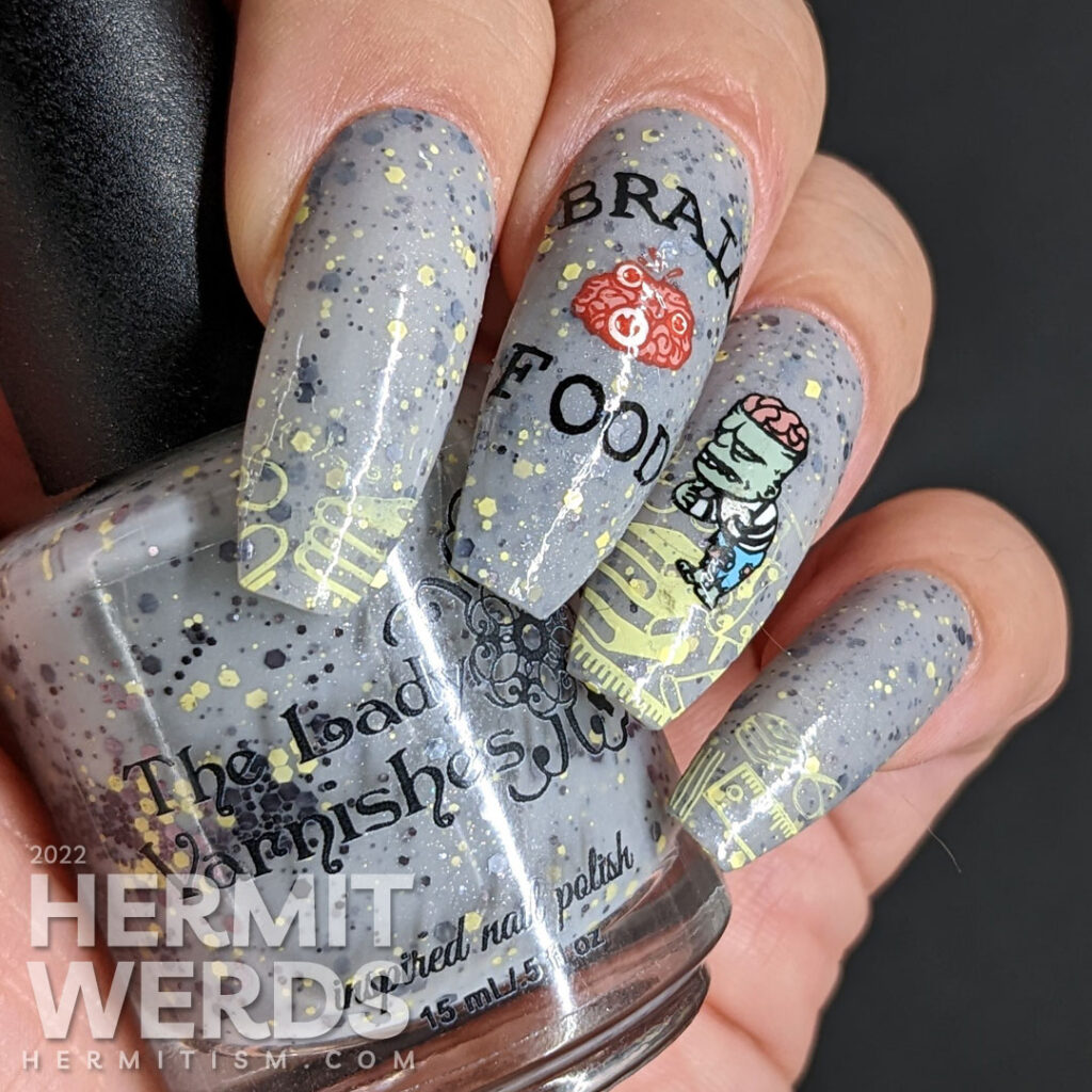 Zombie nail art on a grey crelly with stamping images of academic stuff, "Brain Food" w/brain, a zombie + a school being attacked by zombies.