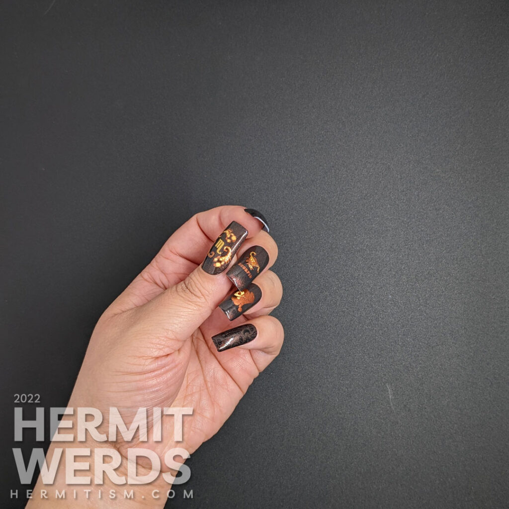 A black magnetic Scorpio nail art with stamping images of desert things, a scorpion lady, and beautiful scorpions in coppers and oranges.