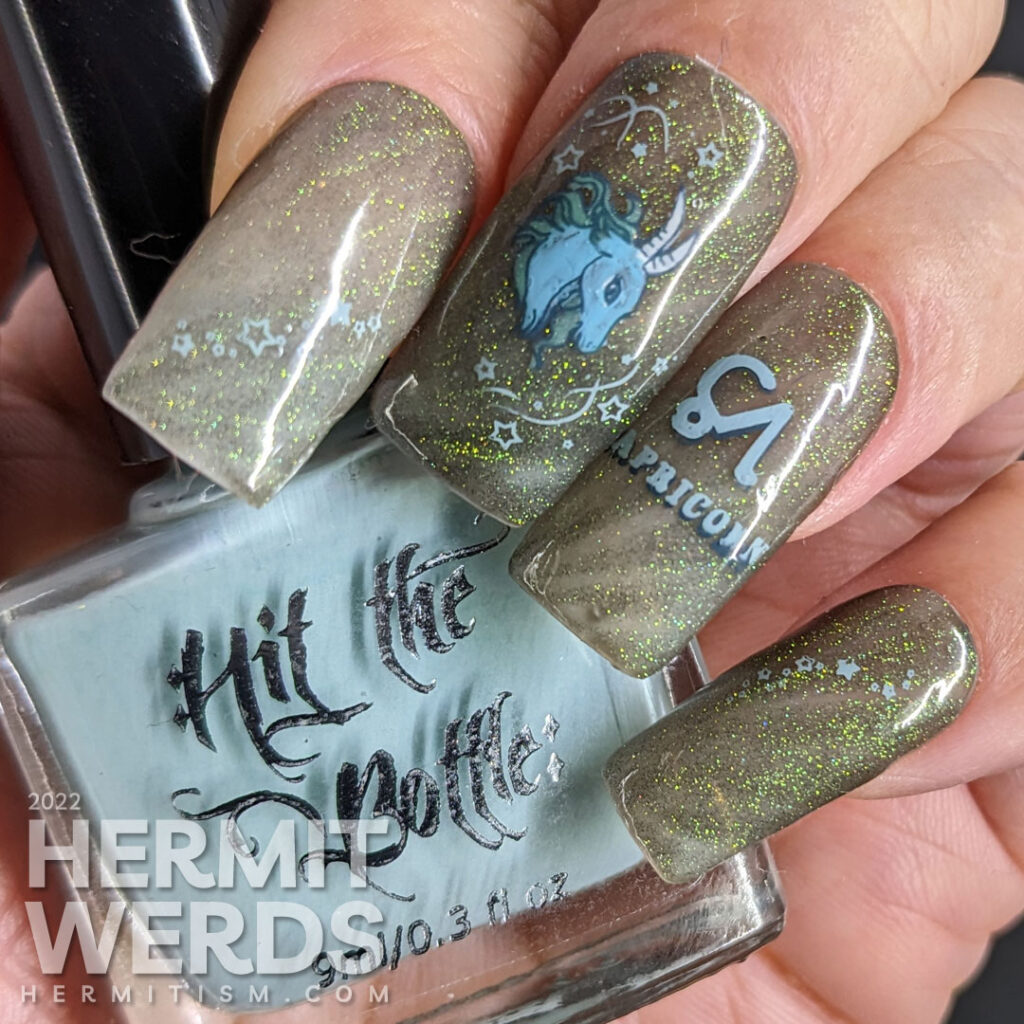 A silvery grey Capricorn nail art using magnetic gel that gives an almost reflective glitter look w/Saturn, symbol, and sea goat head + tail.