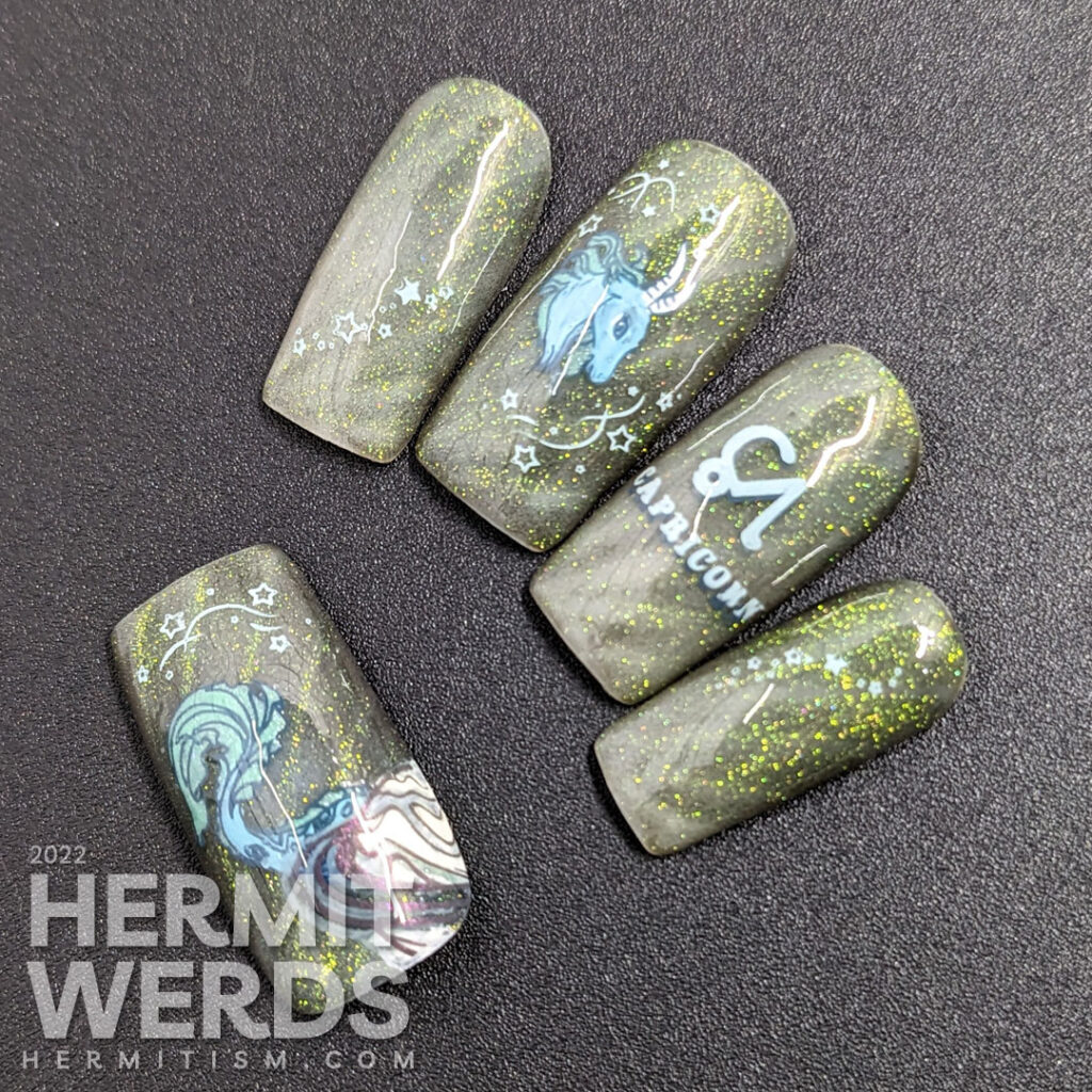 A silvery grey Capricorn nail art using magnetic gel that gives an almost reflective glitter look w/Saturn, symbol, and sea goat head + tail.