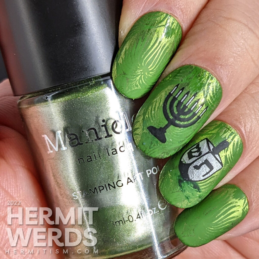 Happy Hanukkah nail art featuring menorah and dreidel stamping decals on a rich, green patterned background.