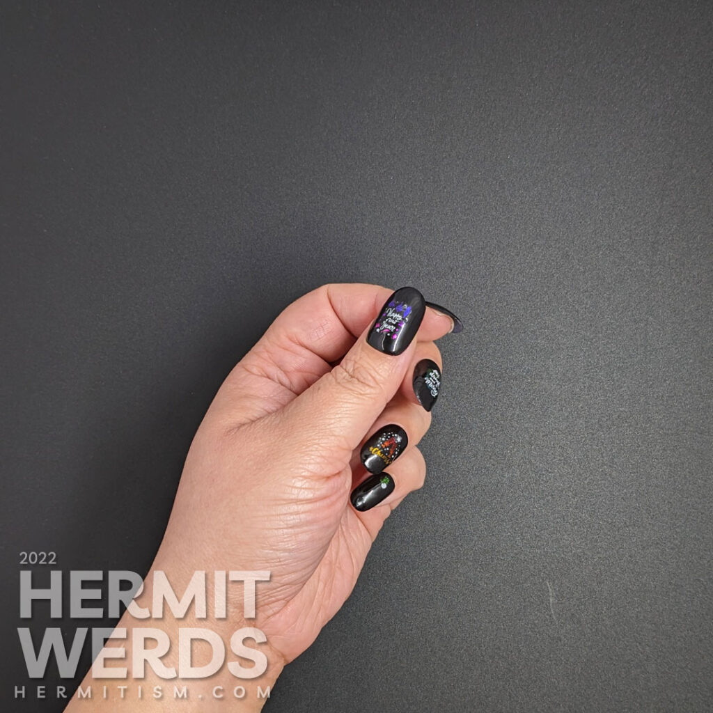 A glossy black holiday season nail art with shiny rainbow nail stickers with white accents offering cheers to a New Year.