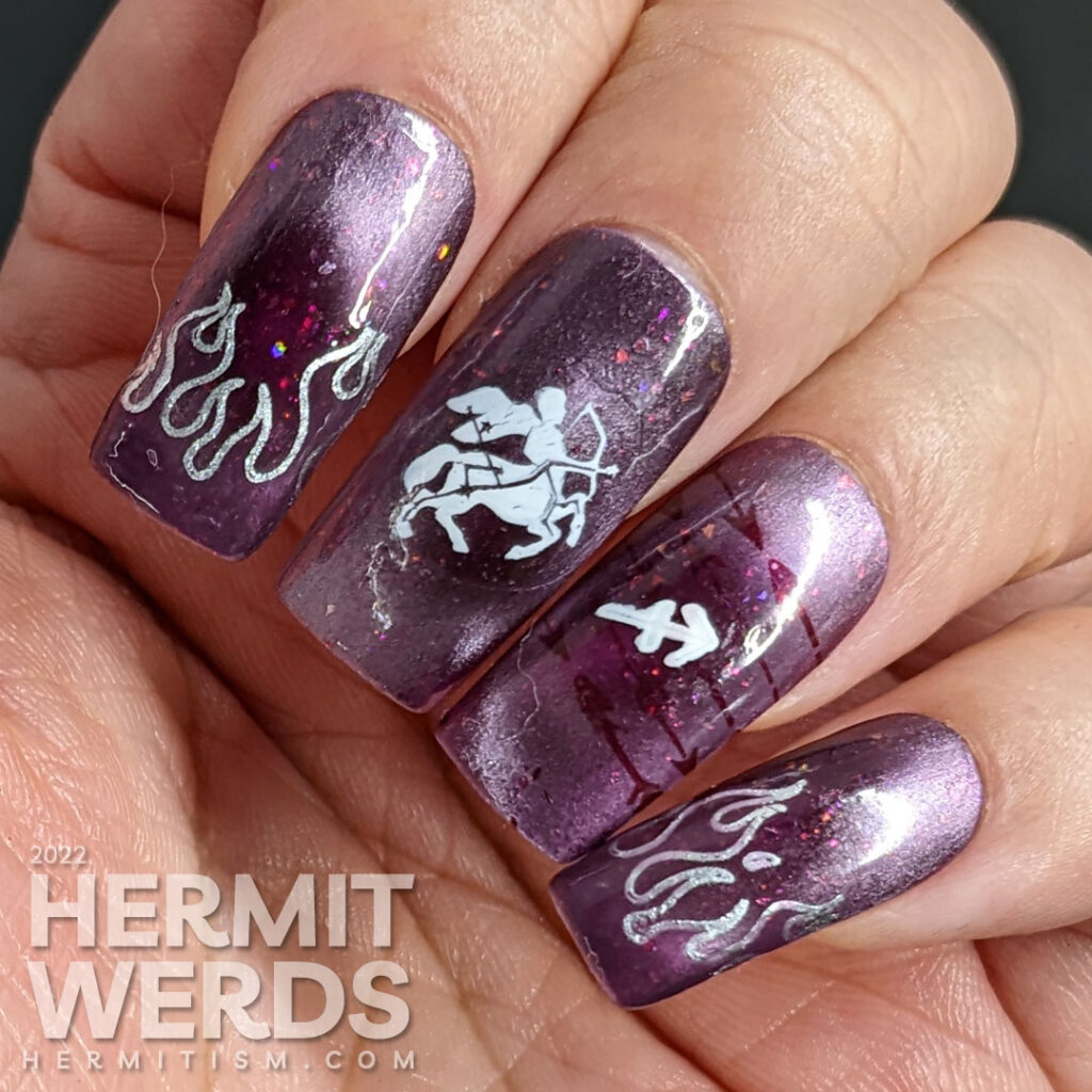 Sagittarius nail art featuring the archer centaur and Sagittarius symbol on a burgundy magnetically pink polish with flakies and holo glitter.