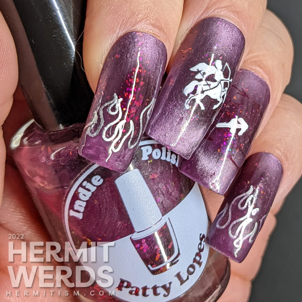 Sagittarius nail art featuring the archer centaur and Sagittarius symbol on a burgundy magnetically pink polish with flakies and holo glitter.