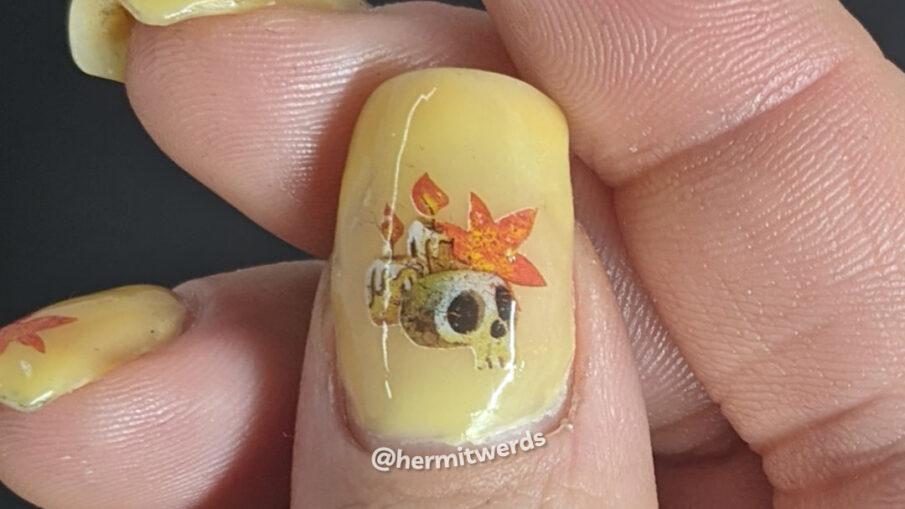 Autumnal nail art on a yellow/orange/brown thermal polish with skull, candle, and autumn leaf water decals on top.