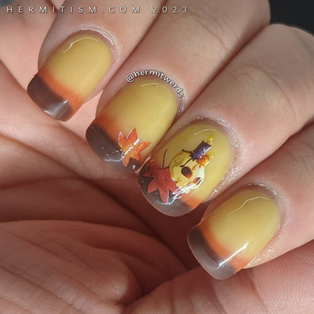 Autumnal nail art on a yellow/orange/brown thermal polish with skull, candle, and autumn leaf water decals on top.