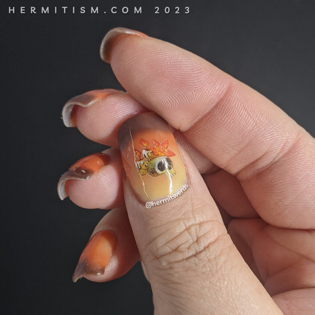 Autumnal nail art on a yellow/orange/brown thermal polish with skull, candle, and autumn leaf water decals on top.