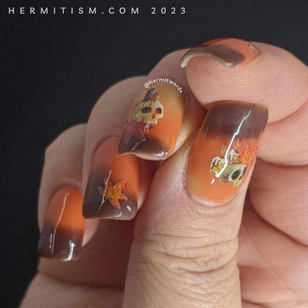 Autumnal nail art on a yellow/orange/brown thermal polish with skull, candle, and autumn leaf water decals on top.