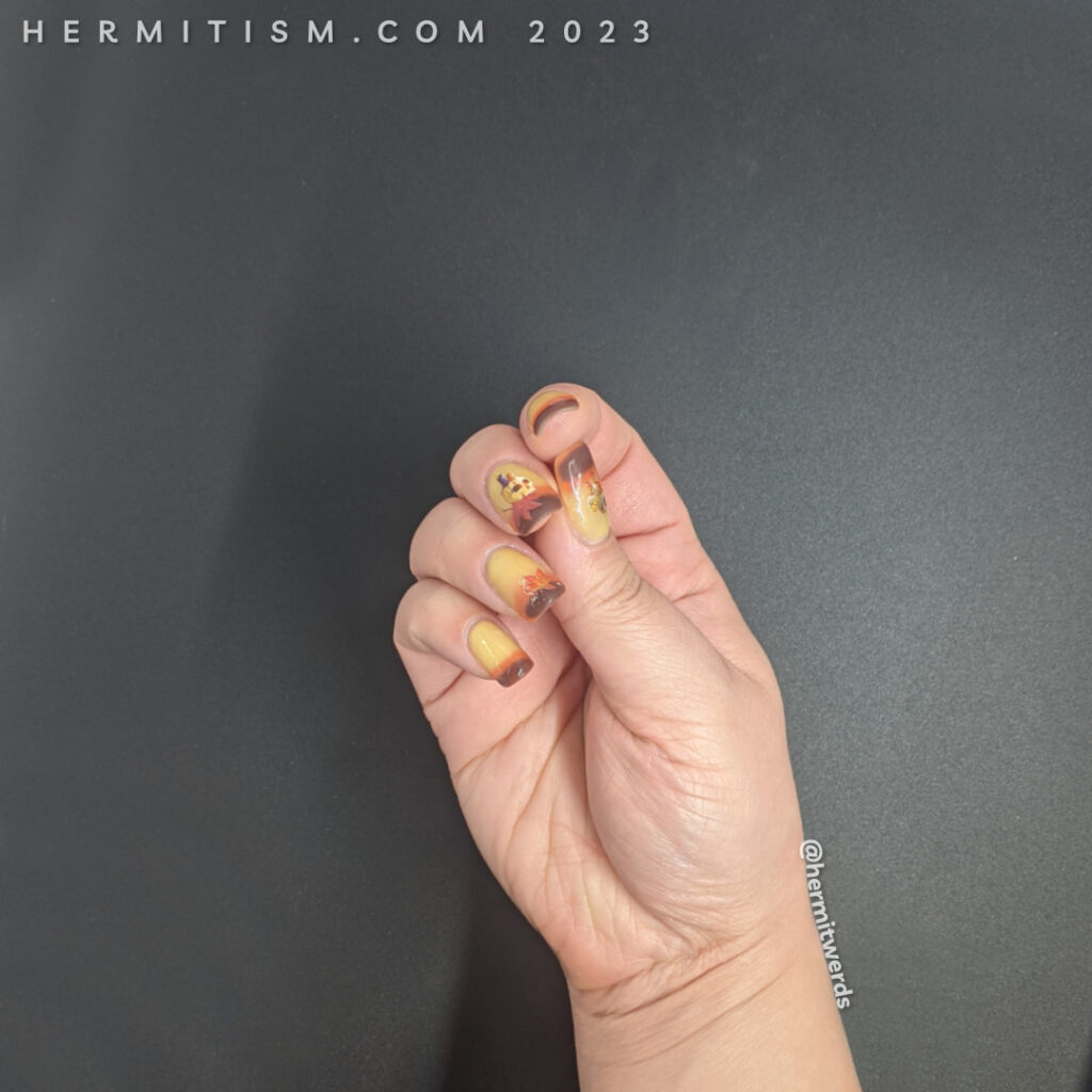 Autumnal nail art on a yellow/orange/brown thermal polish with skull, candle, and autumn leaf water decals on top.