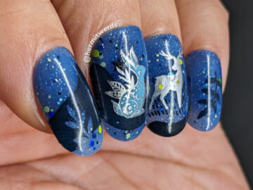 A celestial animal nail design with decals of a silver-outlined celestial deer, rabbit, and owl on a blue jelly sky with starry glitter.