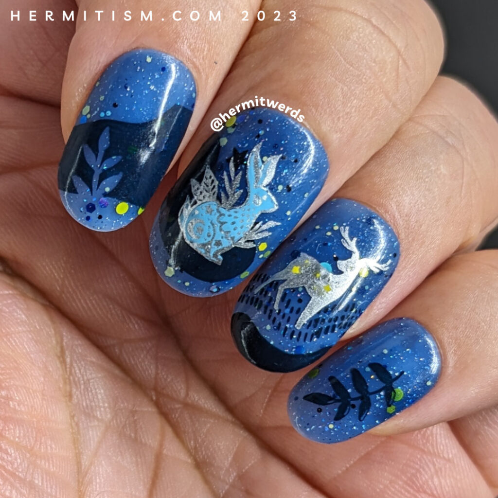 A celestial animal nail design with decals of a silver-outlined celestial deer, rabbit, and owl on a blue jelly sky with starry glitter.