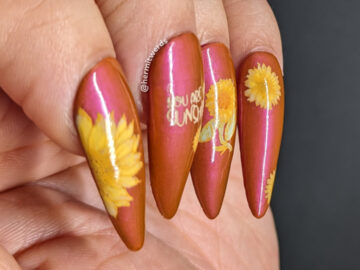Beautiful sunflower nail art in soft yellows on a shimmery orange background with a wicked flipside stamping of spiders on their webs.