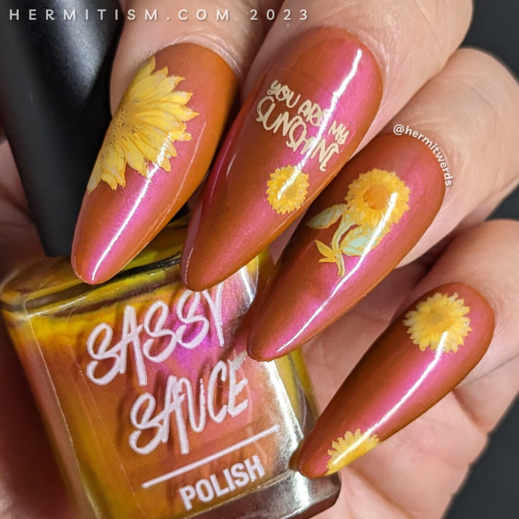 Beautiful sunflower nail art in soft yellows on a shimmery orange background with a wicked flipside stamping of spiders on their webs.