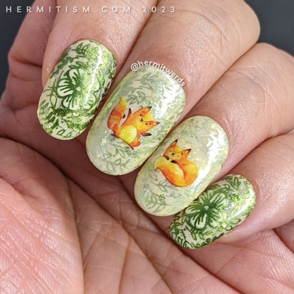 A sweet fox nail art using watercolor-esque fox water decals on top of a pale yellow crelly base with metallic floral prints stamped on top.