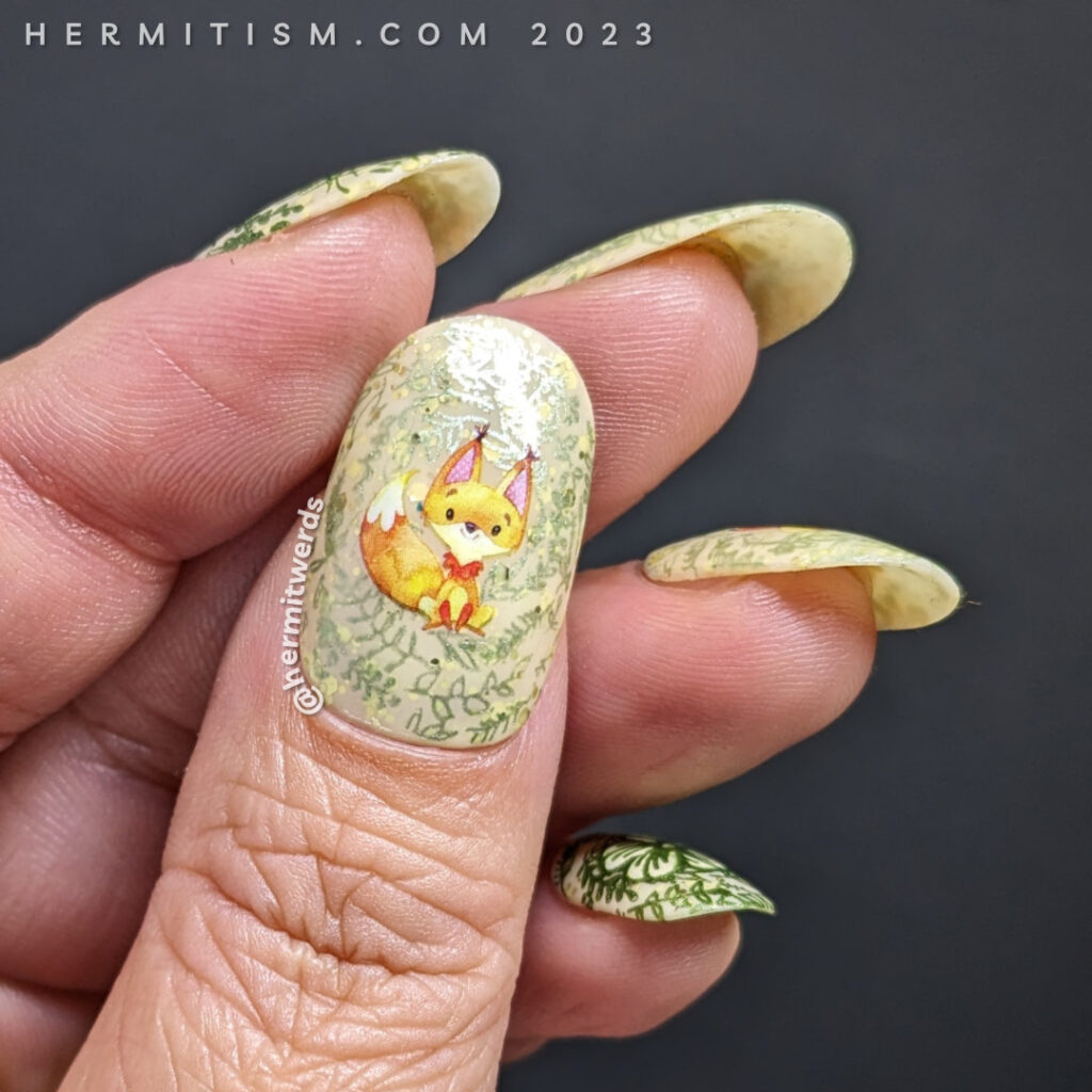 A sweet fox nail art using watercolor-esque fox water decals on top of a pale yellow crelly base with metallic floral prints stamped on top.