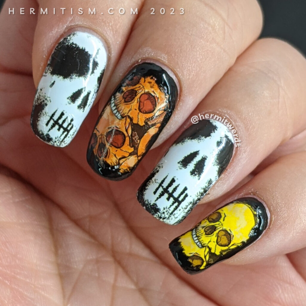 Skull nail art with skull water decals in white, black, orange, yellow, and green on a white background with black sponged around the edges.