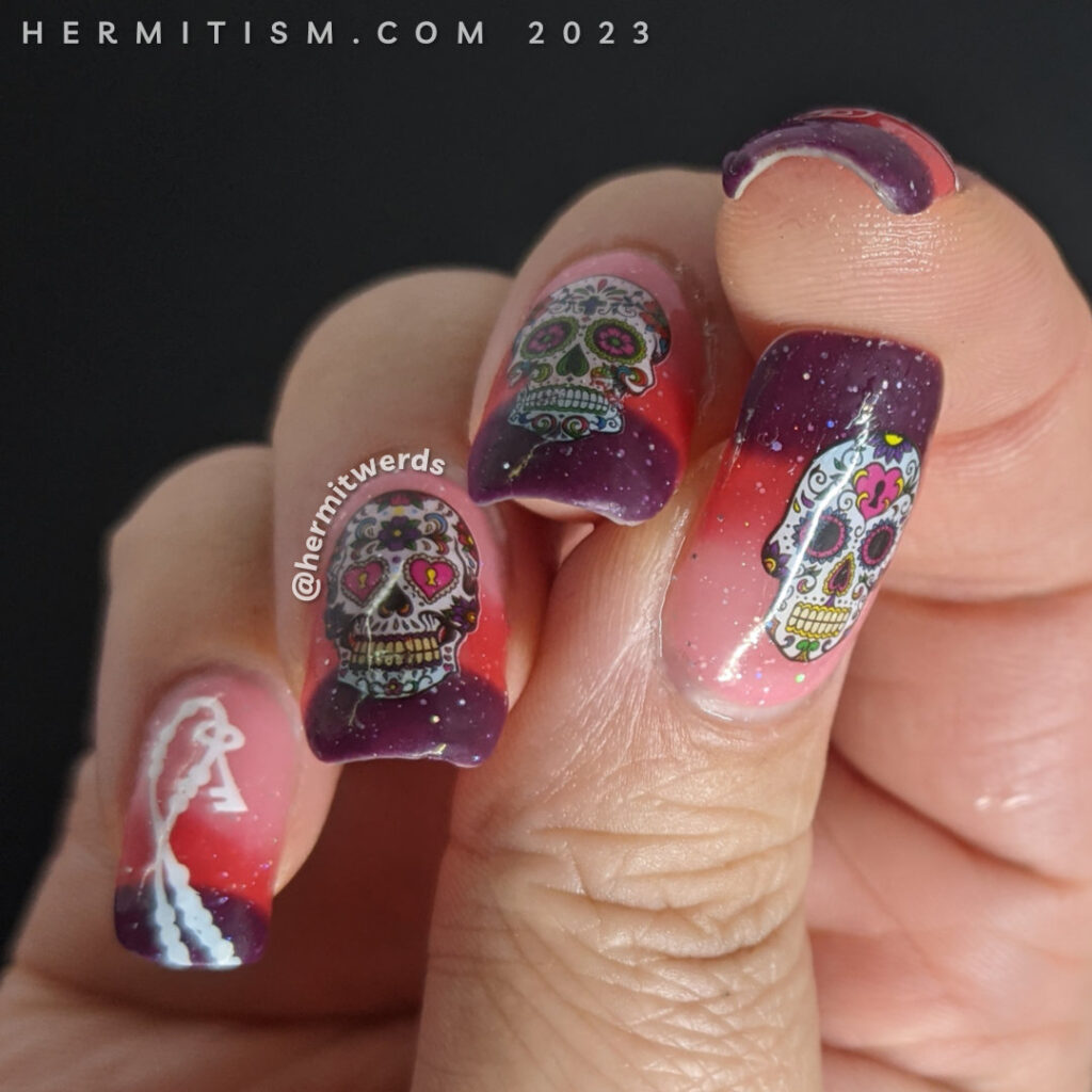 Day of the Dead (Día de los Muertos) water decals of ornate sugar skulls on a thermal holographic polish that moves from pink to purple.