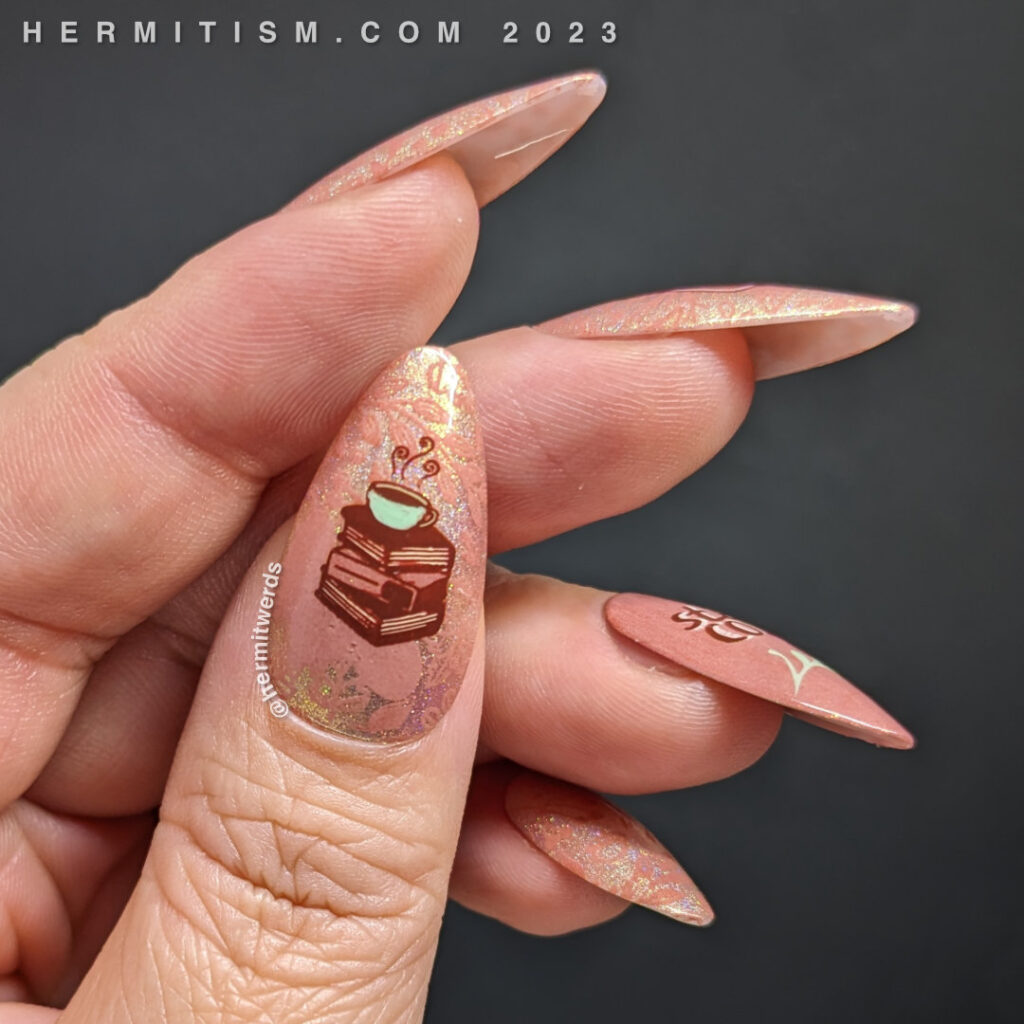 A peachy hygge tea nail art with stamping decals of a tea pot, a stack of books with a tea cup, and "stay cozy" decorated with leaves.