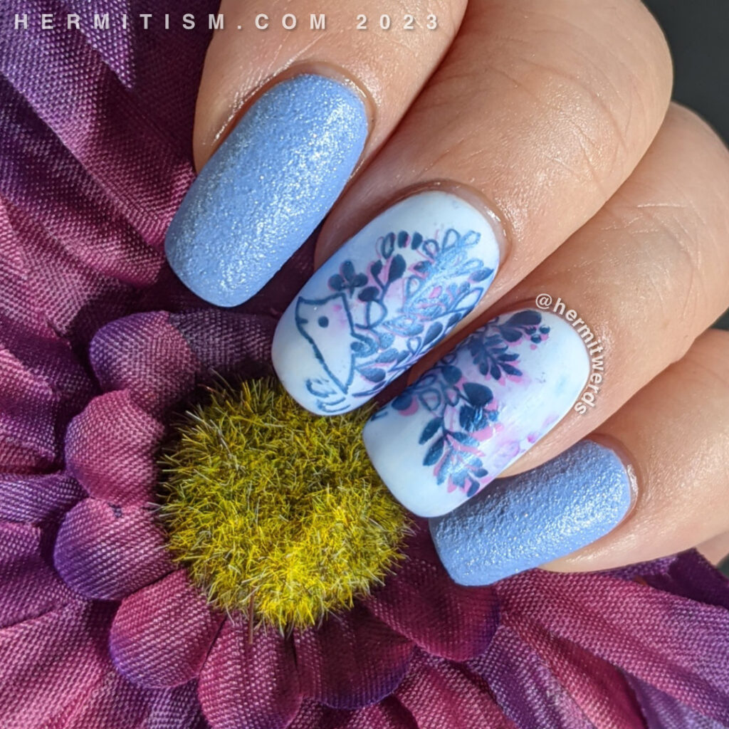 A blue on blue hedgehog nail art design with a double stamped floral hedgehog framed by light blue texture polish.