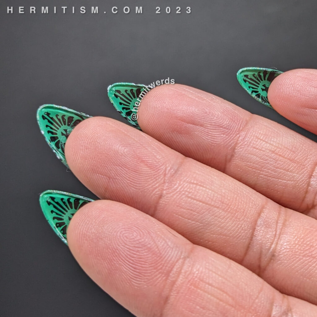 Flipside nail art with an art deco flourish stamped on the underside of green false nails. Art deco nail art for Christmas.