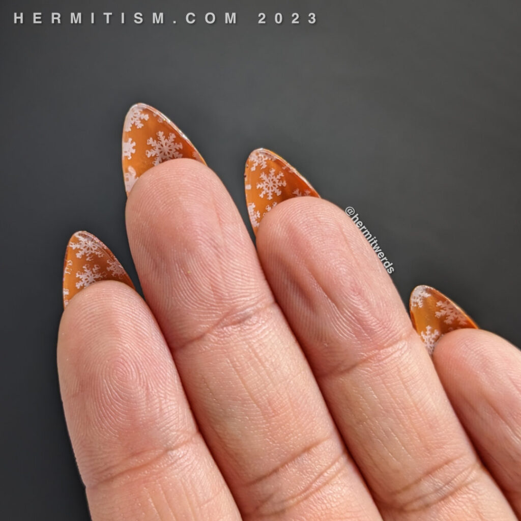 The flipside of a hot chocolate mani with nail stamped snowflakes against a caramel colored backgaround.