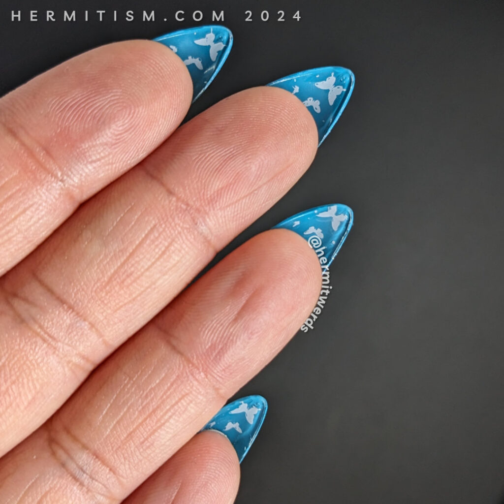 Butterfly nail art in bright blue with swirls of magnetic particles and star fields with butterflies stamped on top. Flipside butterflies.