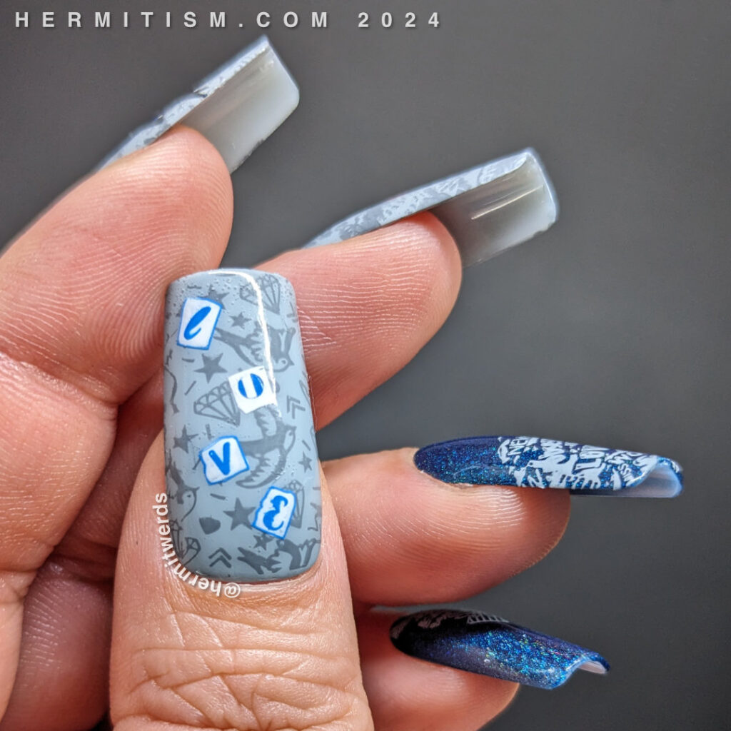 Love bird nail art with tons of newsprint, hearts, "love" and two sweet blue birds in flight on a grey/blue or holographic blue background.