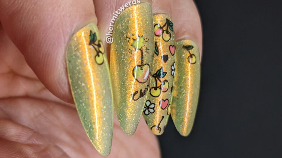 Yellow cherry nail art on a sunny yellow super shifty polish with reverse stamping of a cherry "bomb", yellow cherries, hearts, and flowers.