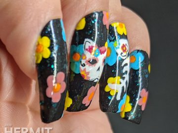 Sugar skull nail art for the Day of the Dead on black jelly teal glitter fake nails with freehand painted cat and fish sugar skulls and flowers.