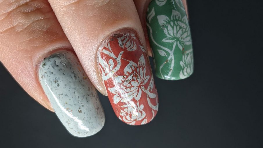 A grey crelly with flakies that shift from red, orange, gold, yellow and green with floral negative space stamps in red and green.