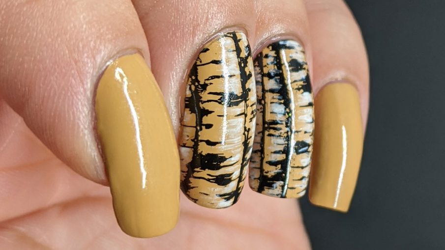A tan nail art with birch tree trunk stamping images highlighted with white nail polish and frolicking birds.
