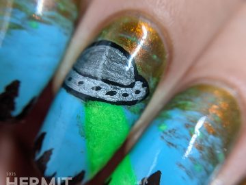 A freehand UFO nail art design with an multichrome olive/red and blue sky, silver UFO with glow in the dark tractor beam and stars.