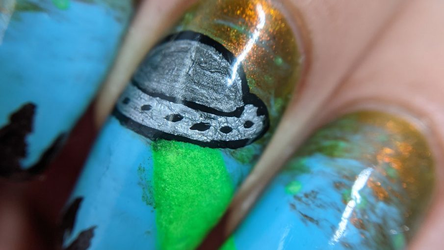 A freehand UFO nail art design with an multichrome olive/red and blue sky, silver UFO with glow in the dark tractor beam and stars.