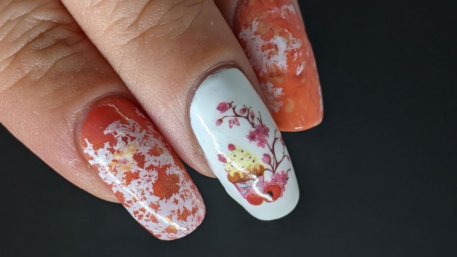A cupcake nail art with a cupcake water decal accent nail and creamsicle-like water spotted nails in white, orange, and coral.