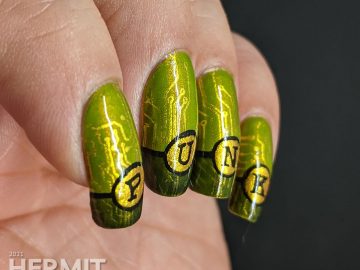 A green gold circuit board mani with "PUNK" French tips and a cyberpunk mohawked lady on the thumb.