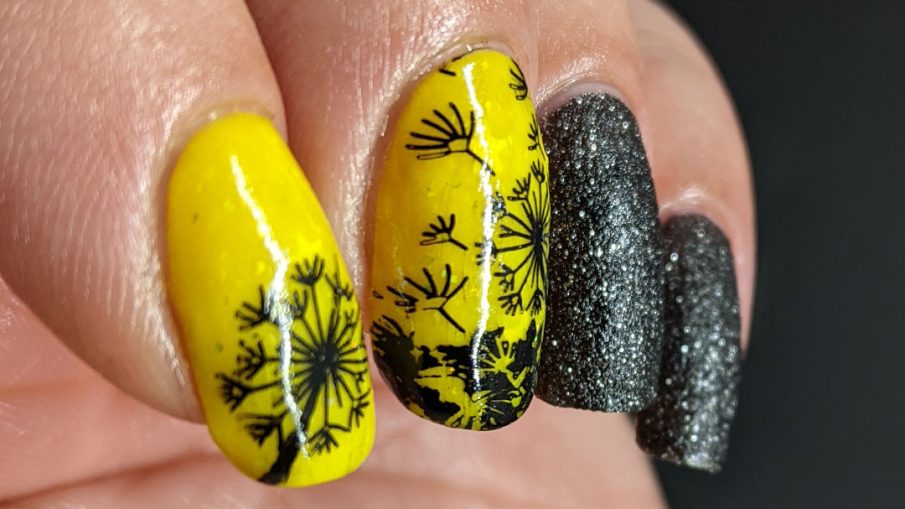 A neon yellow crelly and black texture polish manicure with negative space black dandelions stamped on top. Glows in the dark.