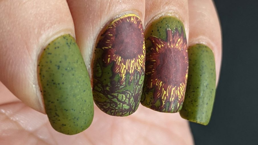 Autumn-esque nail art of yellow, orange, and brown sunflower stamping decals on an olive green speckled nail polish base.