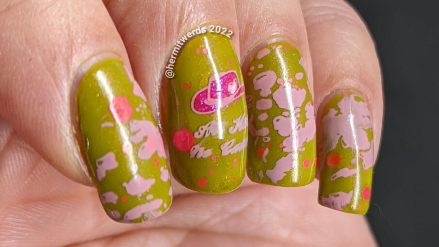 Cowgirl nail art on a green base with pink glitters, pink stamping decals of pink cowhide print, cowboy hat, and cowgirl with a "bang" flag.
