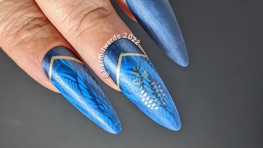 Golden pineapple nail art on blue stiletto falsies with a beautiful art deco lace pattern stamped in the background and half moons.