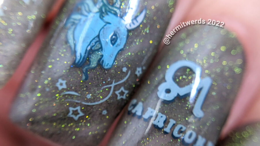 A silvery grey Capricorn nail art using magnetic gel that gives an almost reflective glitter look w/Saturn, symbol, and sea goat head + tail.