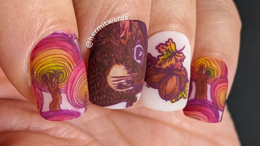 Squirrel nail art with reverse stamping a realistic squirrel and some walnuts and leaves but mostly a tree pattern in a fall rainbow.