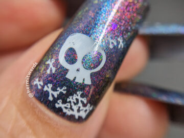 Simple skull and crossbones nail art on a purple/pink magnetic multichrome background filled with flakies and blue magnetic pull.