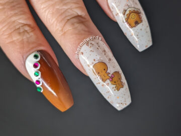 A gingerbread nail art with a Christmas tree and gingerbread people, house, and reindeer stickers and frosted edges with rhinestone gumdrops.